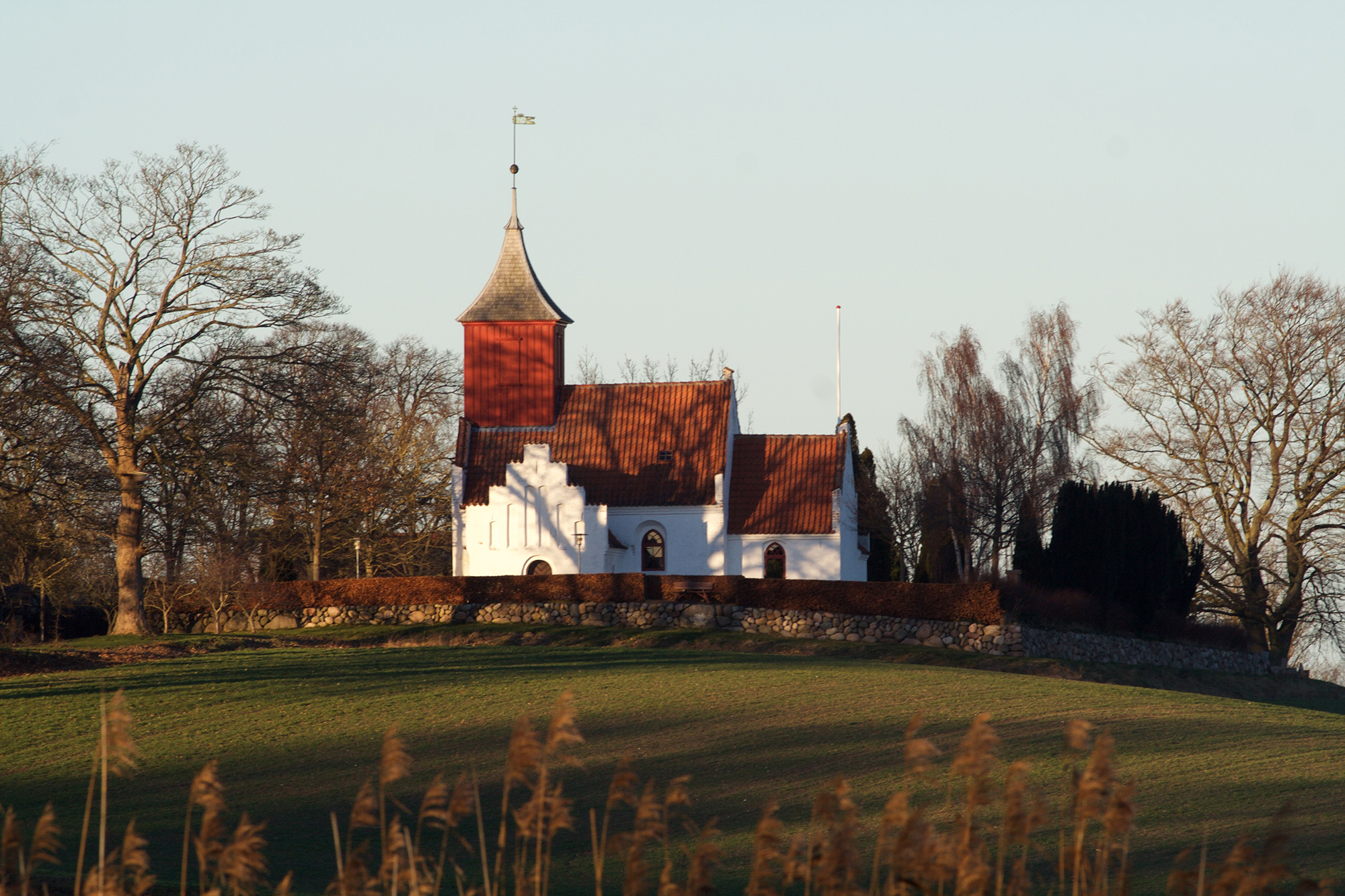 Kornerup kirke set fra sydøst hen over Kornerup Sø. Kornerup kirke er Danmarks mindste kirke med klokkespir